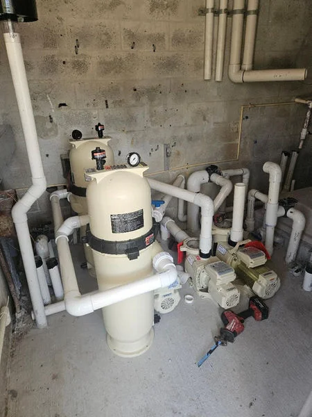 Pool filter system with sand filter tank, pump, PVC piping, and valve manifold installation