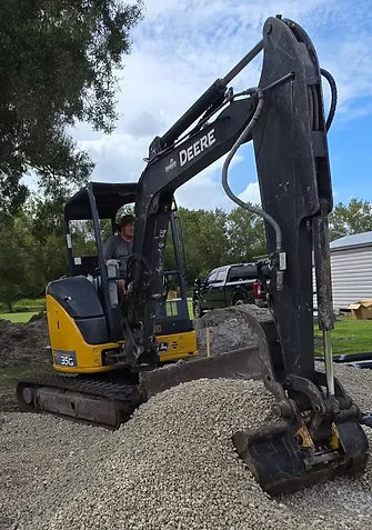 John Deere compact excavator with extended hydraulic arm on gravel site