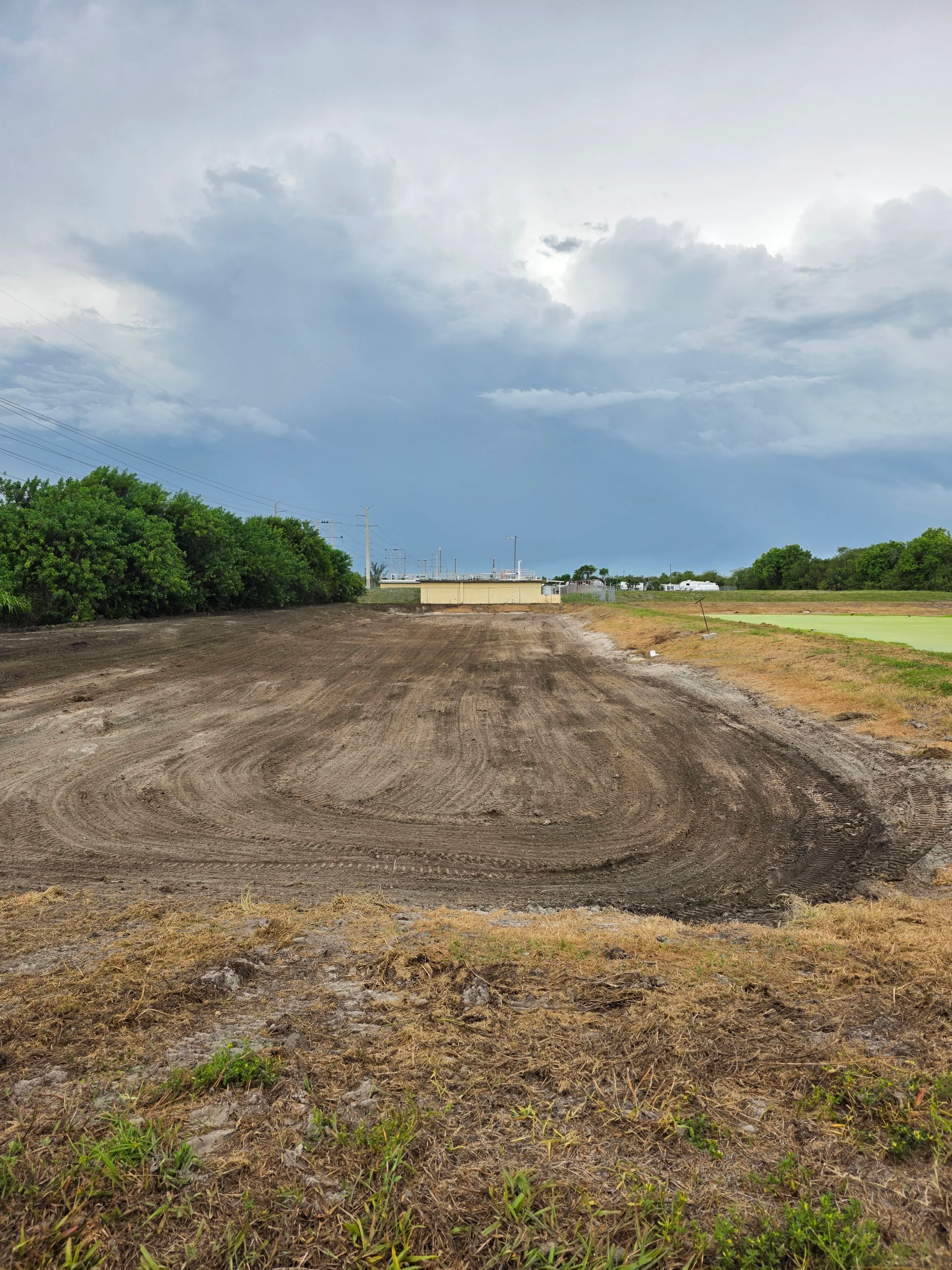Graded dirt lot with compacted soil and heavy equipment grading marks on commercial property