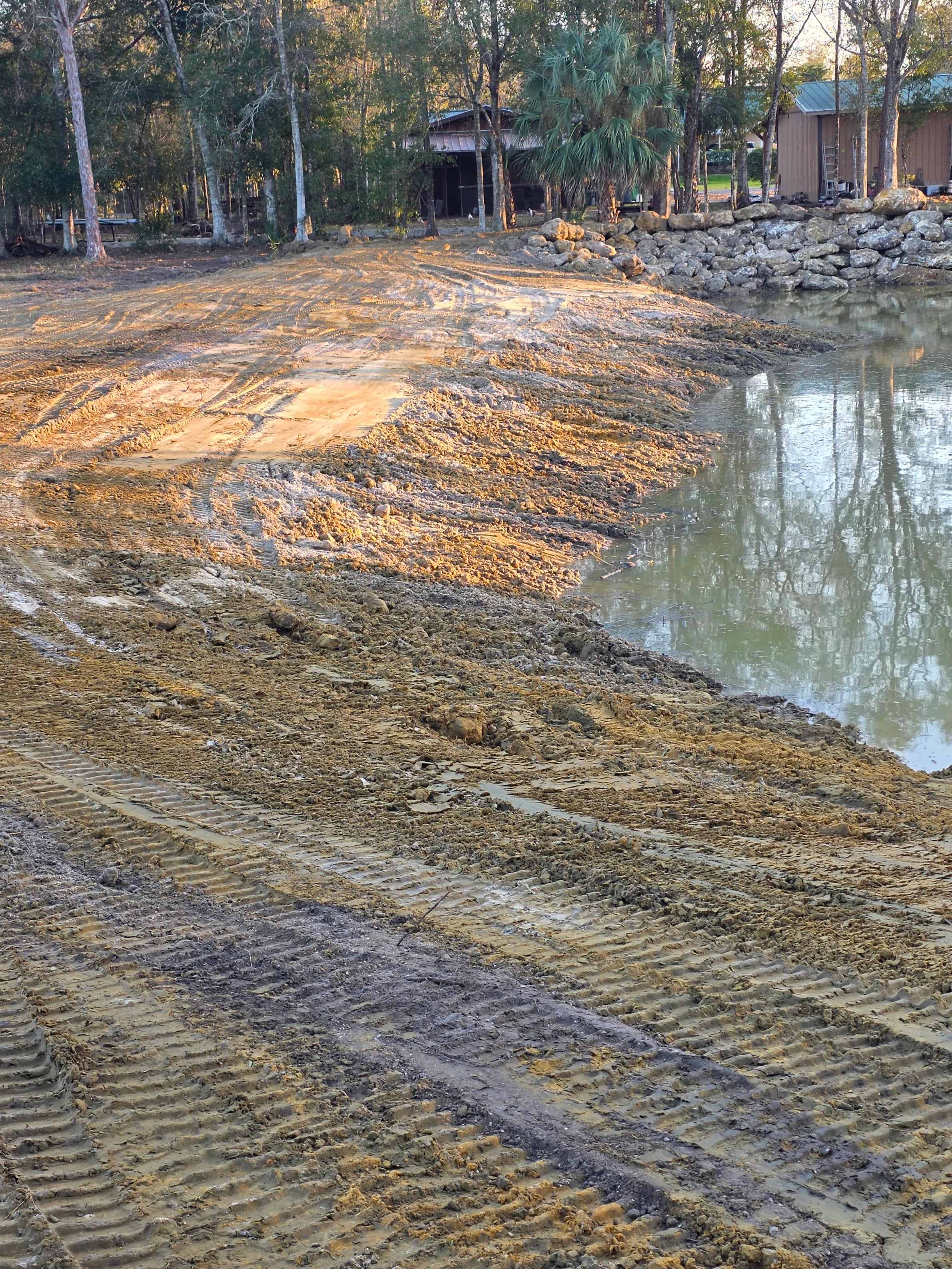 Graded waterfront lot with gravel base, rock erosion barriers, and cleared vegetation